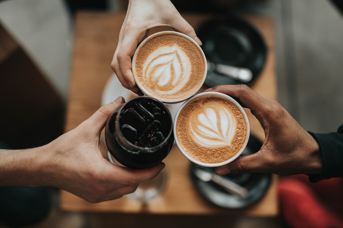 Three friends bringing together freshly prepared coffee drinks